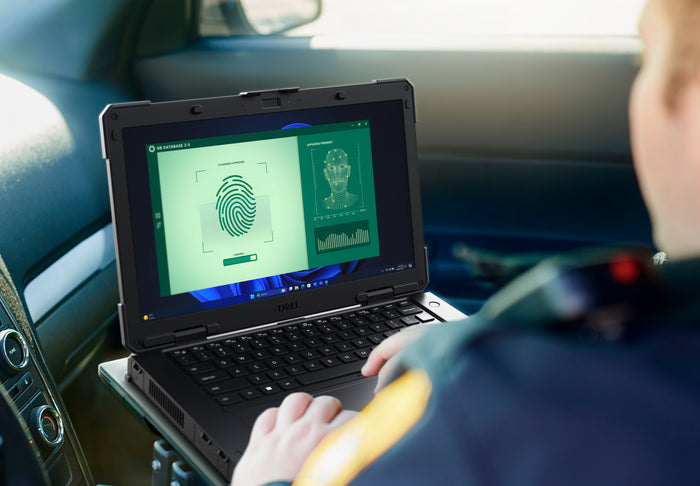 A person in a car uses a rugged Dell laptop to run a fingerprint and face recognition system on the screen.